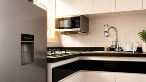 Una cucina moderna con forno a microonde integrato, dispenser per acqua, piano cottura a gas e lavello in acciaio inox.