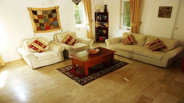 Uma sala de estar com dois sofás brancos, uma mesa de centro de madeira e um tapete estampado.