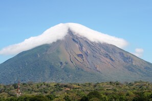 A mountain with a cloud-covered peak and a dense forest at its base.