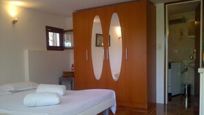 Un dormitorio con cama, armario y baño visible a través de una puerta abierta.