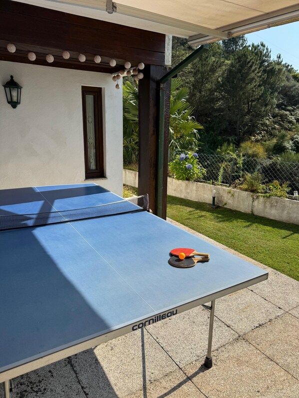 An outdoor ping pong table with a net, two paddles, and a ball. - Casa Dikitaru | Mountain Views & Serenity near the National Park of Peneda Geres (Vieira do Minho)