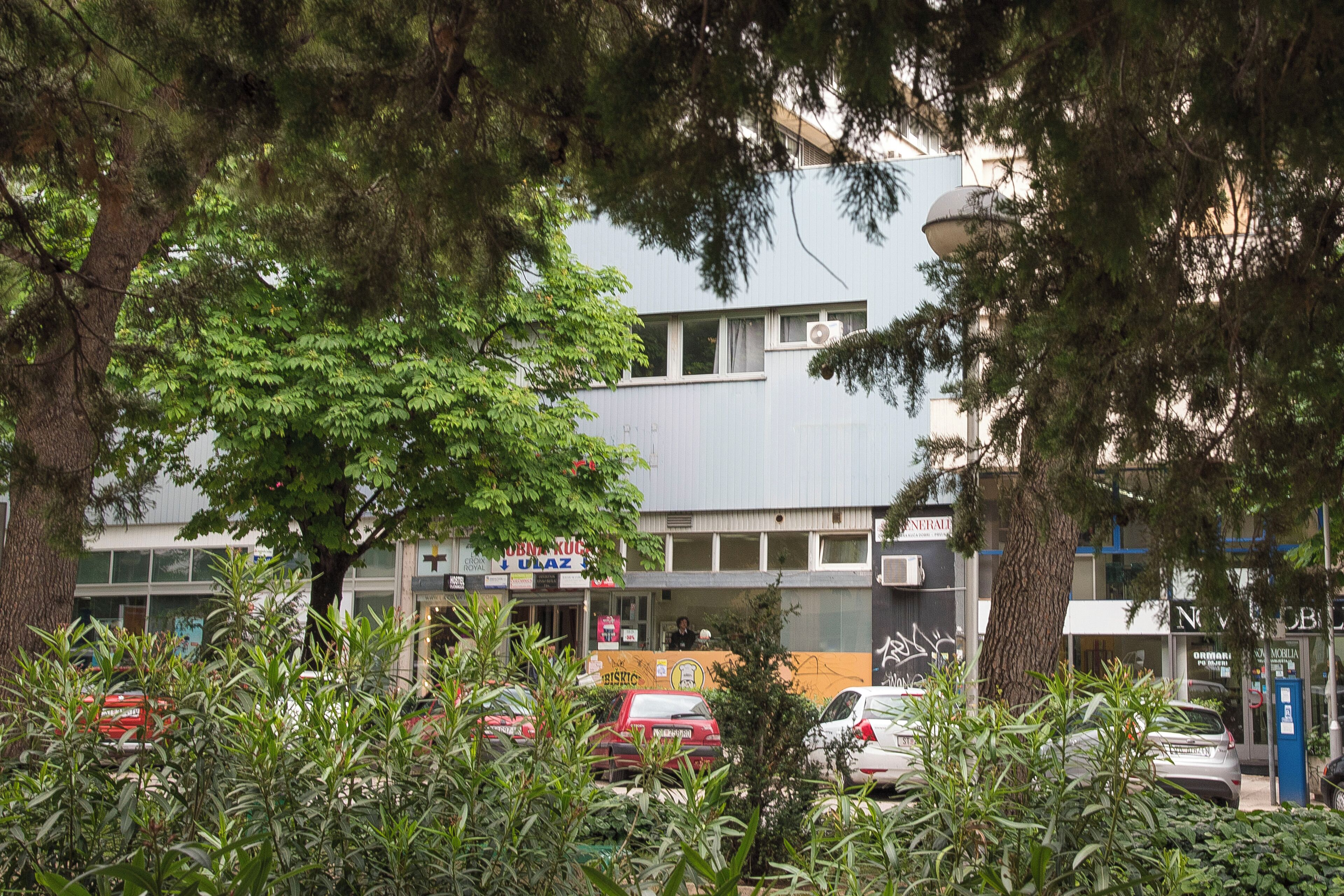 A building with a flat facade, multiple windows, and a visible air conditioning unit.