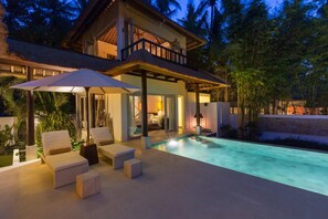 A modern house with a swimming pool, outdoor seating, and a balcony.