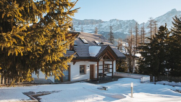 A chalet with a sloped roof, wooden beams, and a snow-covered ground.
