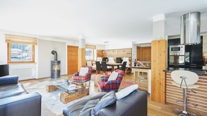 A modern living room with a fireplace, a dining area, and a kitchen with a stove and microwave.