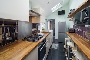 Una cucina moderna con piano di lavoro in legno, elettrodomestici in acciaio inossidabile e forno integrato.