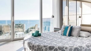 A bedroom with a large bed, a view of the sea, and a balcony with chairs. - Villa Dorado with Pool, Sauna, Jacuzzi, Gym & more (Marsaskala)