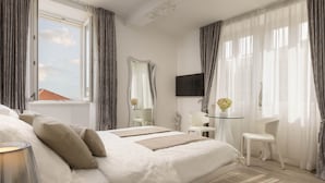 Een moderne hotelkamer met een groot bed, een bureau, een stoel, een televisie en een raam met gordijnen.