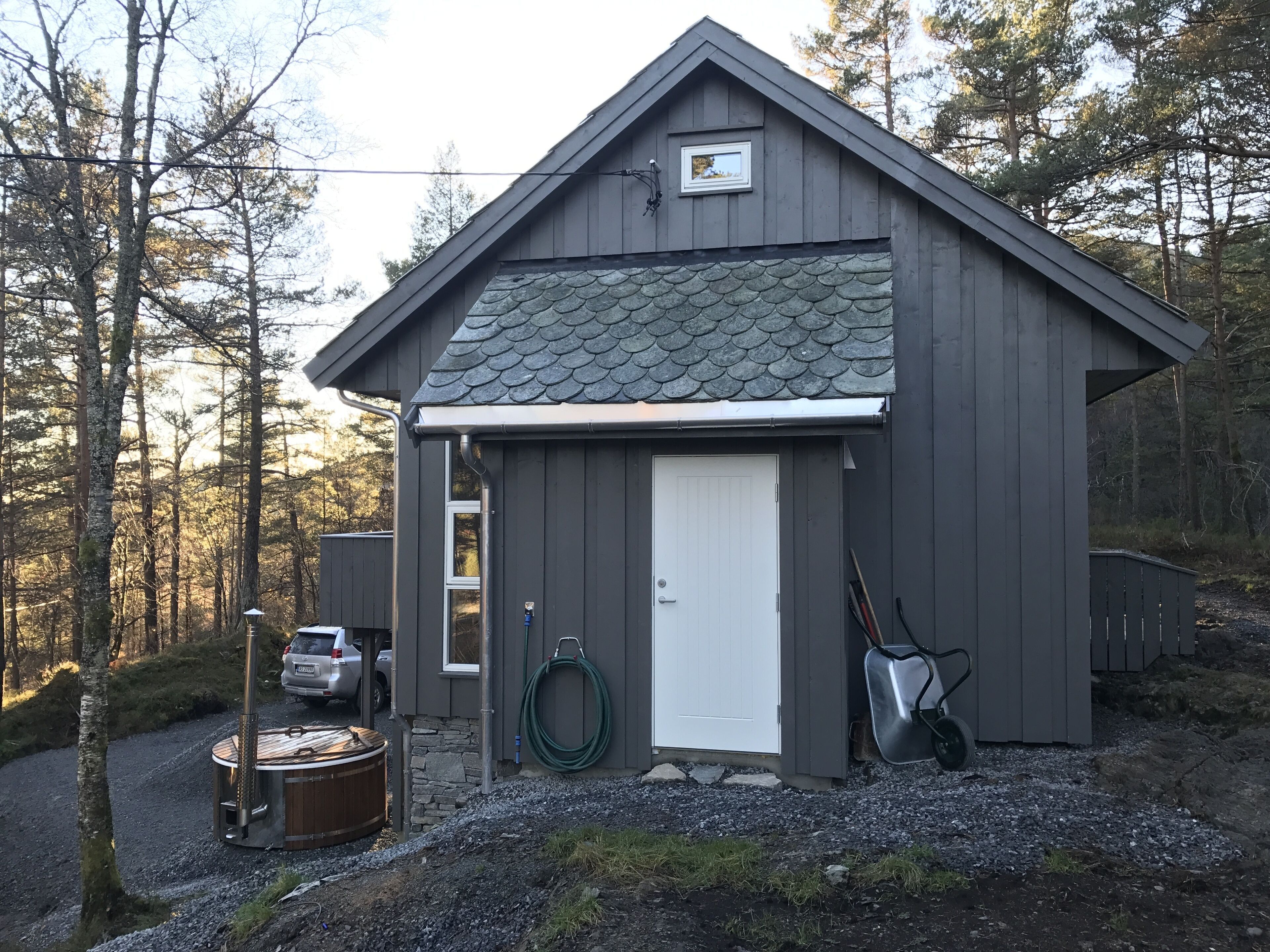 A small, single-story wooden shed with a white door, a metal roof, and a small window.