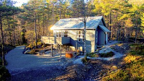 A rustic cabin with a stone foundation, wooden exterior, and a small hot tub. - Fam friendly furniture cottage in a quiet environment. 8 Pers Sauna and Jacuzzi (Stord)