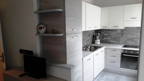 Eine moderne Küche mit weißen Schränken, einem Backofen, einer Spüle und einer Kaffeemaschine.