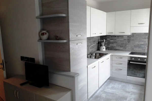 Een koelkast, een oven, een kookplaat, kookgerei, borden en bestek