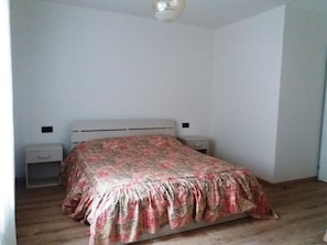 A bedroom with a bed, two bedside tables, and a ceiling light fixture.