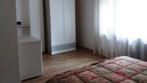 Ein Schlafzimmer mit Bett, Kleiderschrank und einem fenster mit Vorhängen.