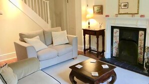 A living room with a sofa, a coffee table, a fireplace, and a staircase. - Grebe Cottage Bonchurch Isle of Wight . Idyllic setting. (Ventnor)