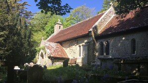 A stone church with a red-tiled roof, surrounded by greenery and flowers. - Grebe Cottage Bonchurch Isle of Wight . Idyllic setting. (Ventnor)