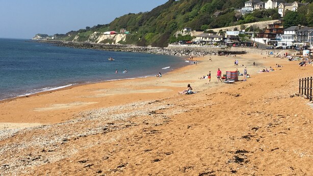 A beach with houses on a hillside, a clear sky, and people enjoying the beach. - Grebe Cottage Bonchurch Isle of Wight . Idyllic setting. (Ventnor)
