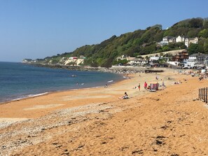 A beach with houses on a hillside, a clear sky, and people enjoying the beach. - Grebe Cottage Bonchurch Isle of Wight . Idyllic setting. (Ventnor)