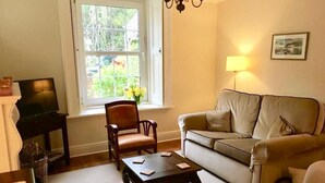 A living room with a sofa, armchair, coffee table, and a television. - Grebe Cottage Bonchurch Isle of Wight . Idyllic setting. (Ventnor)