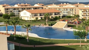 A resort with a swimming pool surrounded by palm trees and a children's play area. - "A JUMP TO PARADISE ........ HOLIDAYS ALL YEAR ROUND". (SAN JORGE)