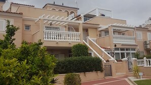 Un edificio residenziale con vialetto in mattoni rossi, balconi bianchi e antenne satellitari.