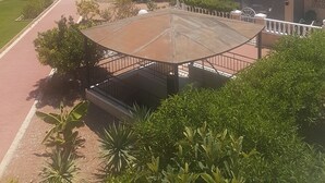 Una zona residenziale con strada asfaltata, palme e case con tetti in tegole.