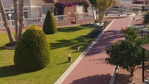 Un quartiere residenziale con un vialetto lastricato, palme e siepi curate.