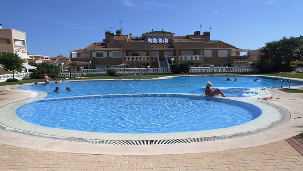 Una piscina dal design curvo, circondata da un vialetto in mattoni.