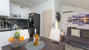 Cocina moderna con microondas, refrigerador y cafetera. Una mesa de comedor con una botella de vino y una copa dispuesta.