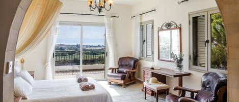 A bedroom with a bed, a chair, a desk, and a view of the outdoors.