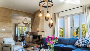 A modern living room with a fireplace, a sofa, a coffee table, and a dining area. - VILLA DEMETRA (4 ensuite bedrooms,  stunning view,BBQ,HighSpeed WI-FI,swim.pool) (Argaka)