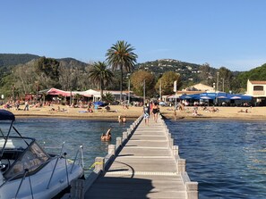A pier leading to a beach with people and boats. - La Croix-valmer: Calm and Relaxation in Lush Greenery, sea View (La Croix-Valmer)