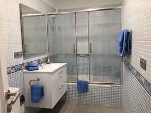Een bad/douchecombinatie, een haardroger, handdoeken, zeep