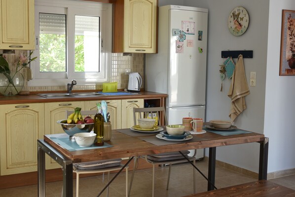 Une cuisine avec une table en bois, un réfrigérateur et divers ustensiles de cuisine.
