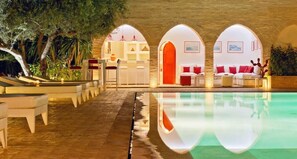 A poolside area with a clear pool, lounge chairs, and a seating area with a red accent wall. - luxury 4 bedroom villa with heated swimming pool, 7 minutes from the center, quiet. (Marrakech)