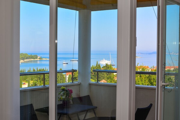 Varanda com vista para o mar, um navio e um cruzeiro ao longe.
