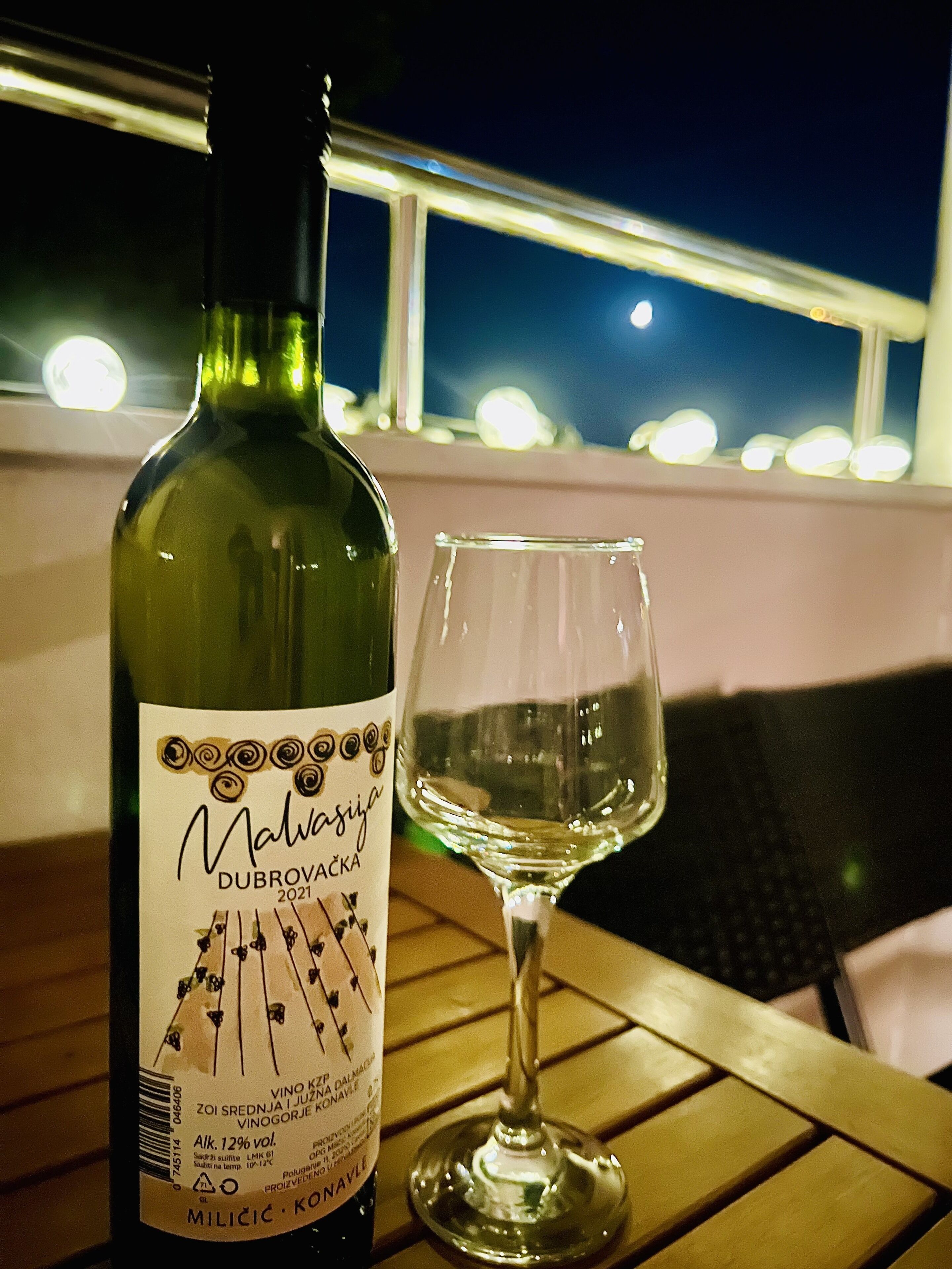 Een fles wijn en een wijnglas op een tafel.