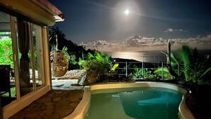 Una piscina con bordo in pietra, un cesto sospeso e vista sul cielo nuvoloso.