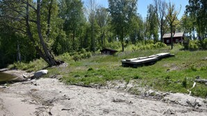 A natural landscape with a wooden dock, a small cabin, and a river.