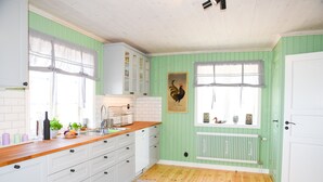 A kitchen with white cabinets, a wooden countertop, and a window with a rooster painting.