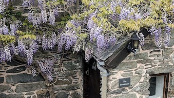 Une maison en pierre avec un petit porche, un luminaire suspendu et une enseigne sur laquelle on peut lire : « The Farmhouse ».