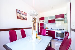 A dining area with a white table, red chairs, and a painting on the wall.