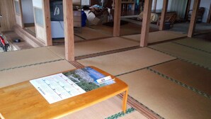 A tatami mat room with a wooden table displaying a map and a calendar. - TETRIS Guest House Kunisato (Isen)