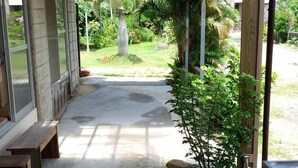 A covered outdoor area with a concrete pathway leading to a garden. - TETRIS Guest House Kunisato (Isen)