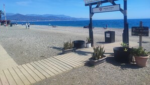 A beach entrance with a sign for Playa Tropical, a beach club, and a sign for Torre del Mar. - Spacious quiet apartment 450 meters to the beach, huge patio, communal pool. (Torre del Mar)