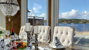 Tavola imbandita con lampadario, bicchieri da vino e candela, con vista su un lago panoramico.