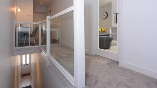 Ein modernes Interieur mit Glastrennwand, Teppichboden und einem sichtbaren Küchenbereich im Hintergrund.