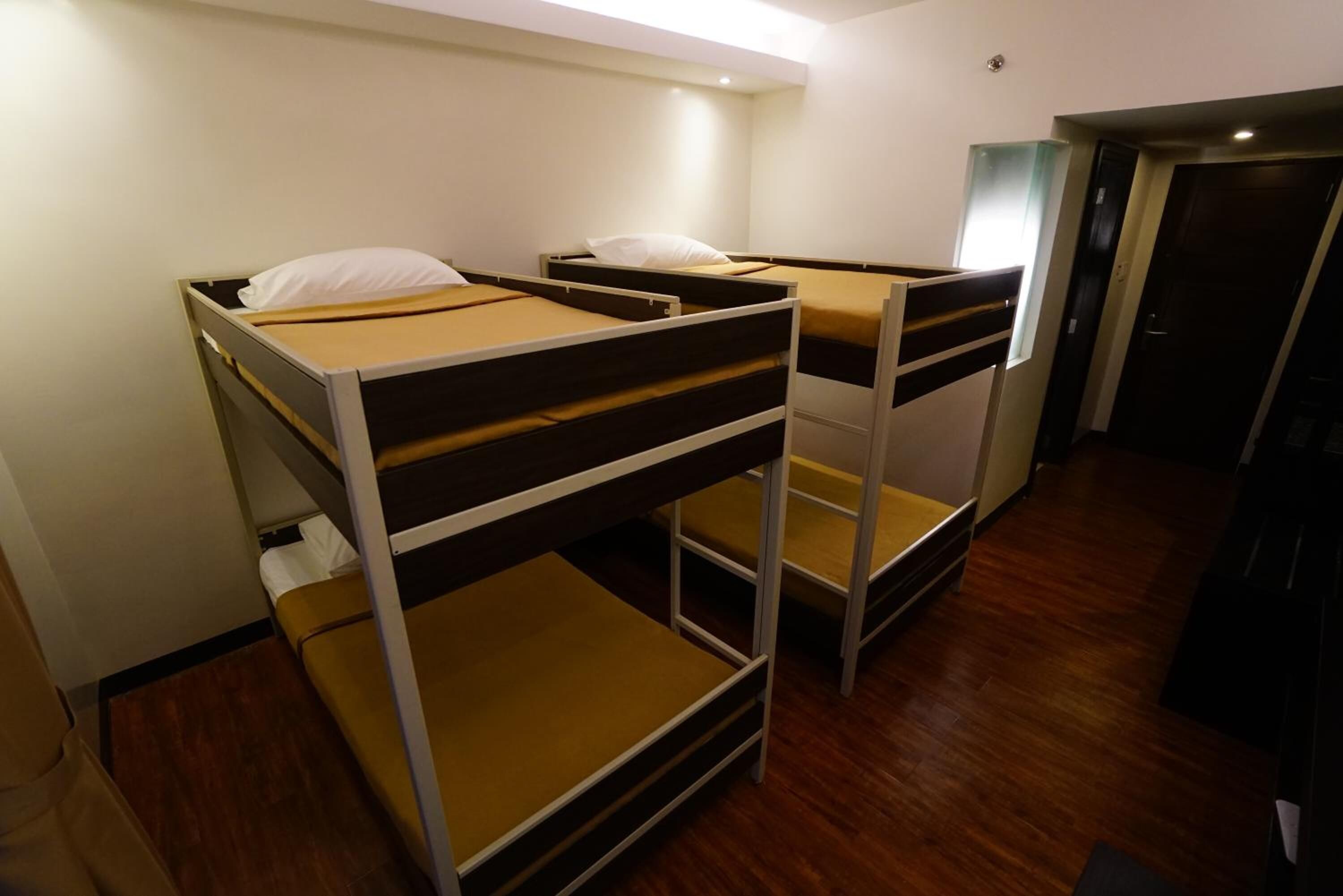 A room with bunk beds, wooden flooring, and a door.