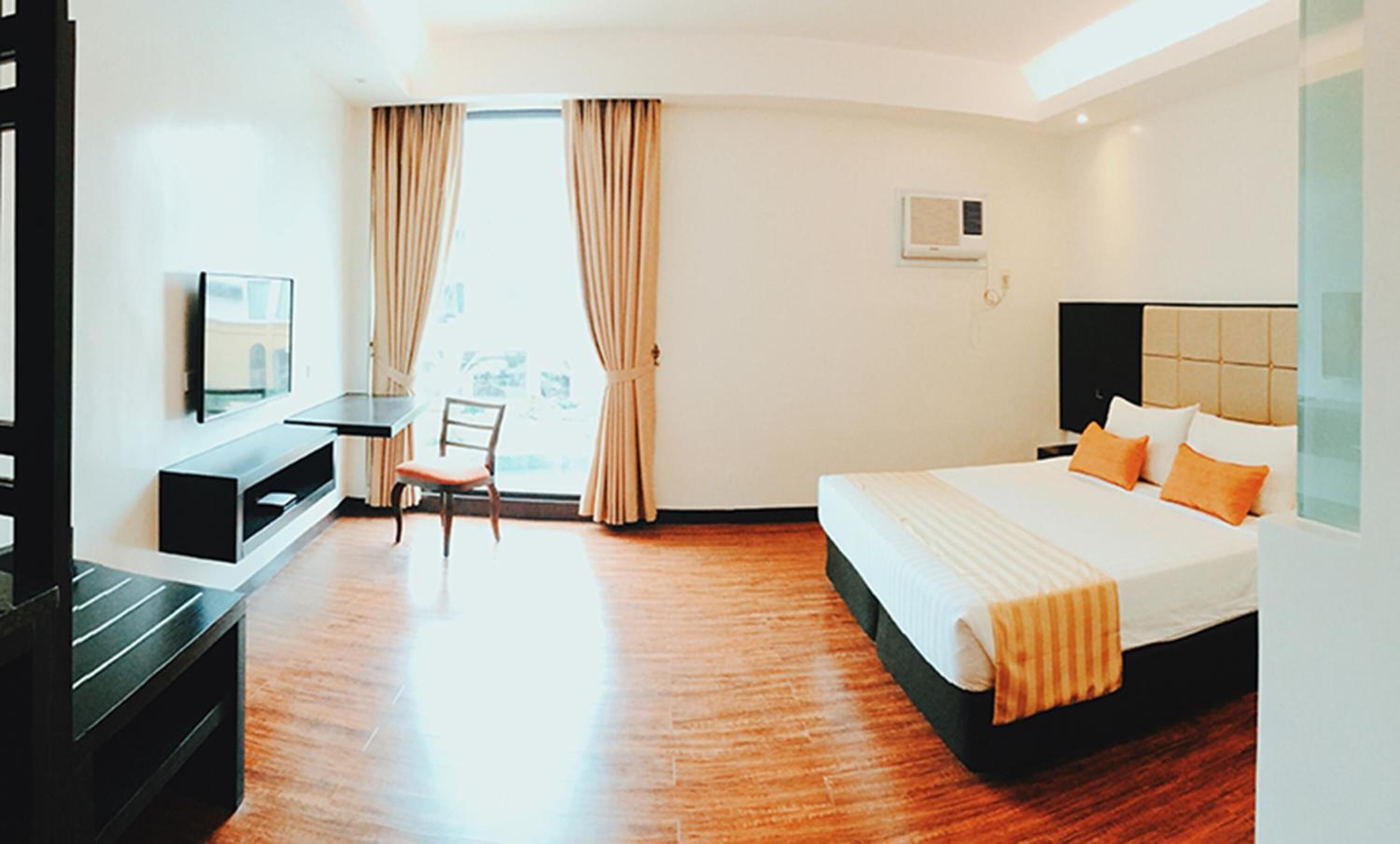 A hotel room with a bed, a desk, a chair, and a television.