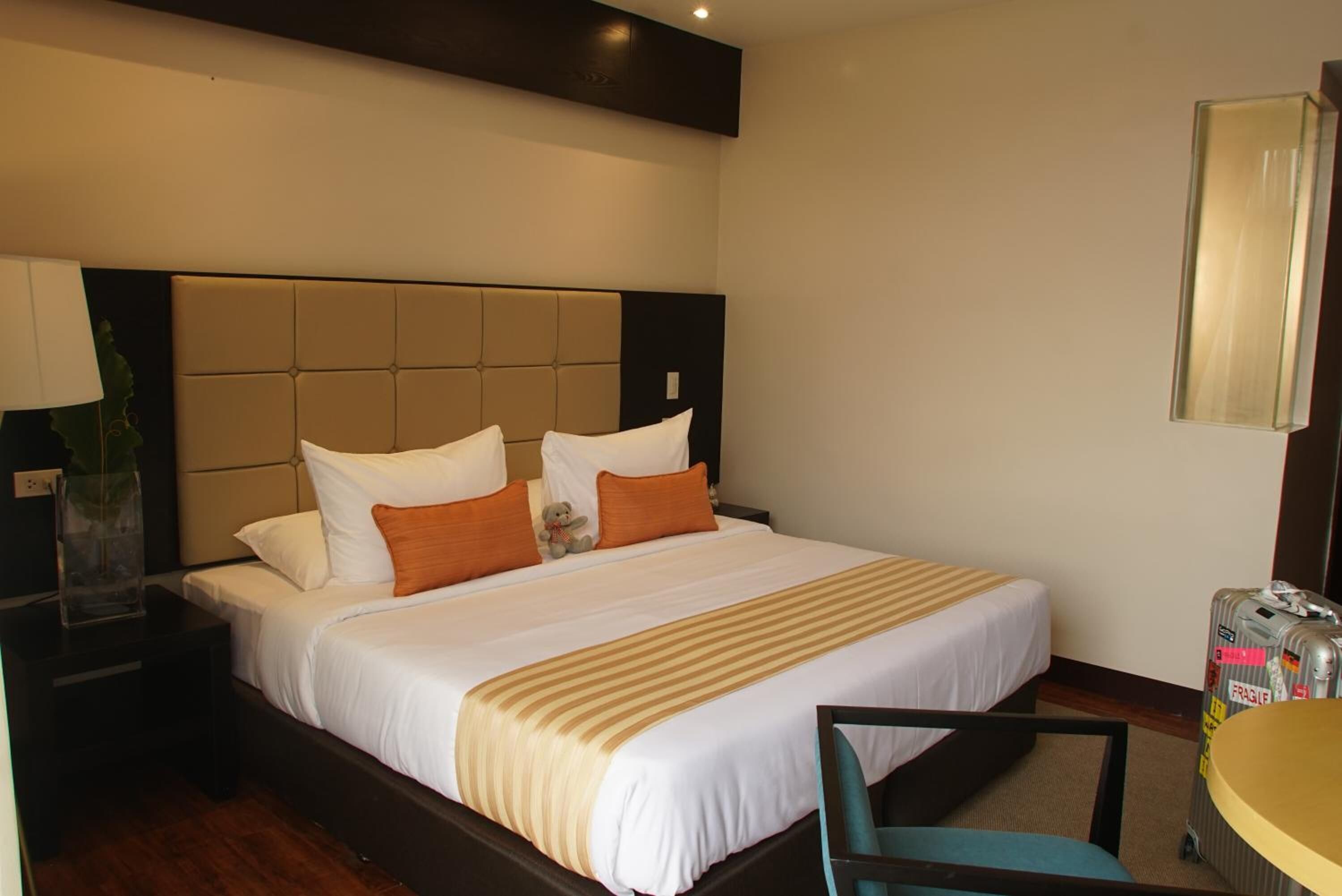 A hotel room with a large bed, a bedside table, a chair, and a small round table.